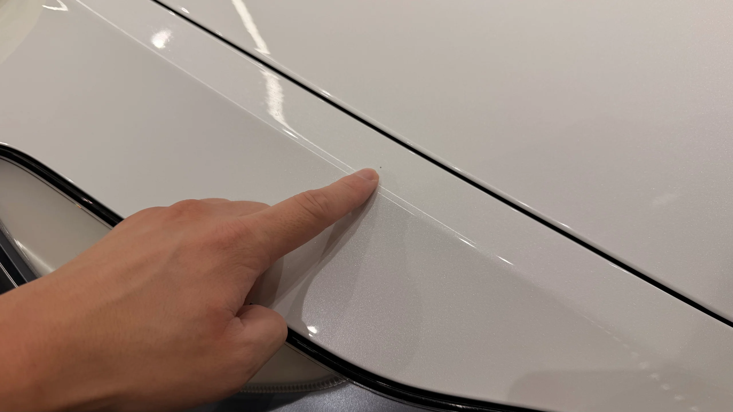 テスラ Model 3のボンネット付近に確認された飛び石による塗装ダメージを施工前に診断している様子